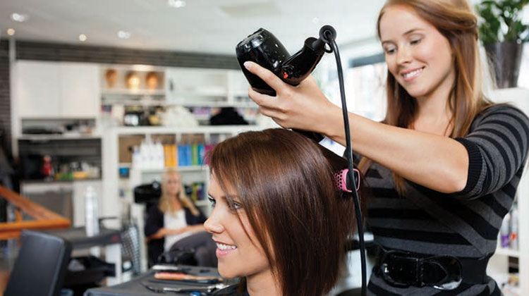 Hair dresser holding a hair dryer with aclient