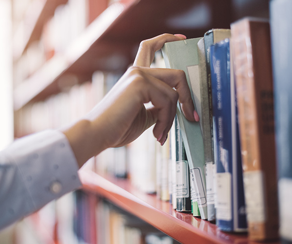 Person pulling a book from a bookshelf.