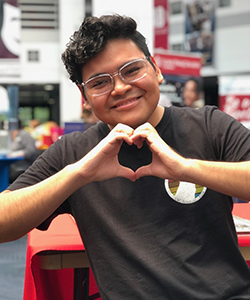 A former SGA leader makes heart hands at an event