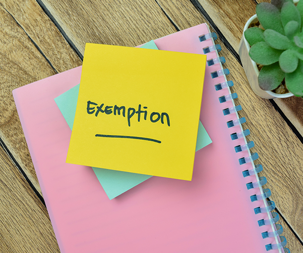 Notebook with a post-it note on top that reads, 'Exemption'.