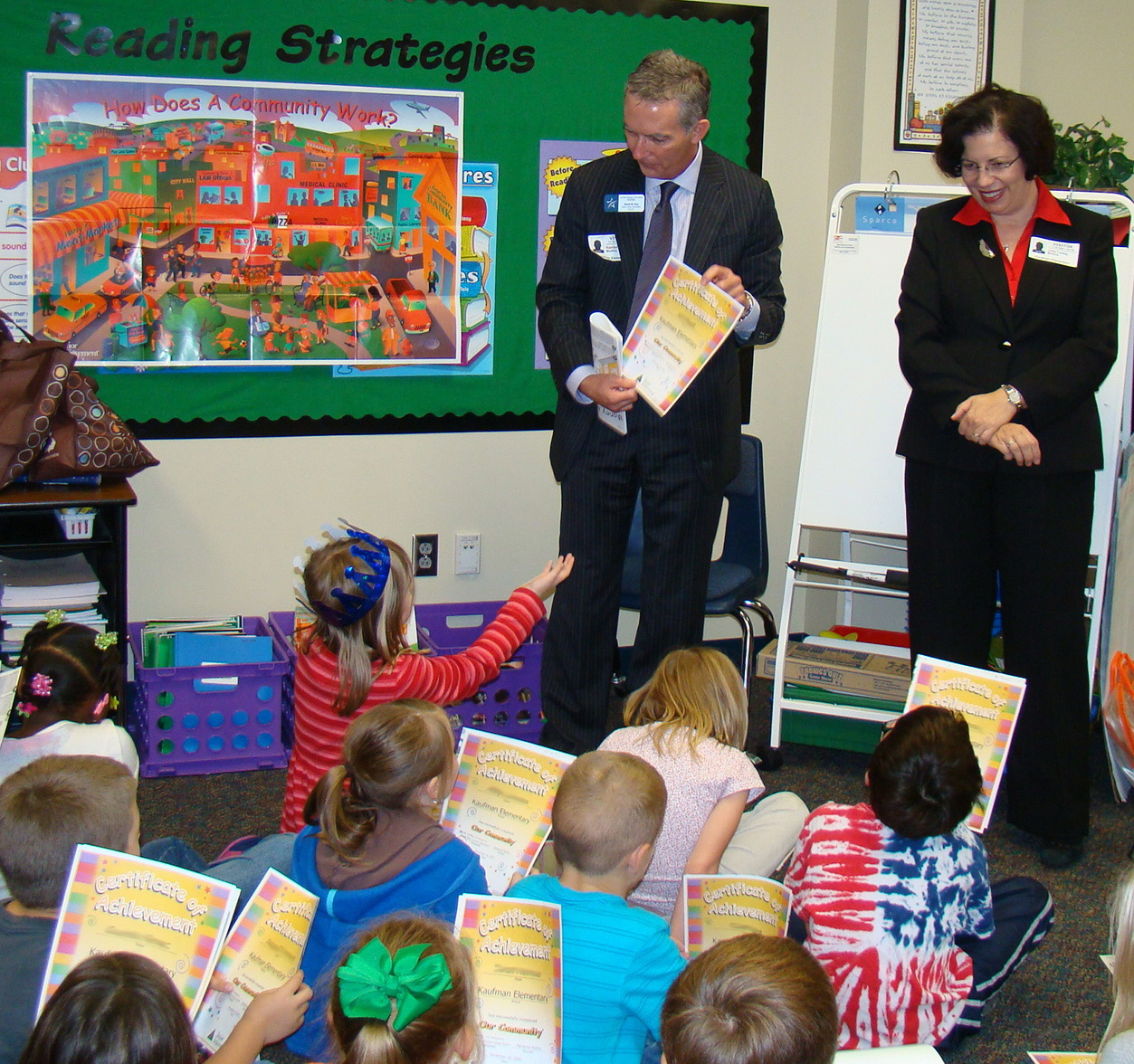 Rand Key and Dr. Julie Leidig, executive administrators from the Lone Star College System, present second-graders at Kaufman Elementary certificates marking their participation in the Junior Achievement program. Key and Leidig were among 40 students, staff, and faculty members from Lone Star College-Montgomery who taught the elementary students.