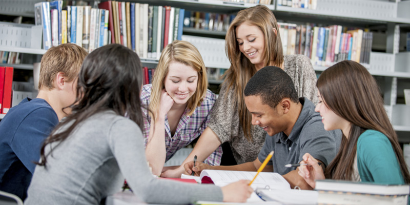 Students working together around a table in library.