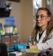 Student in lab coat inside a lab