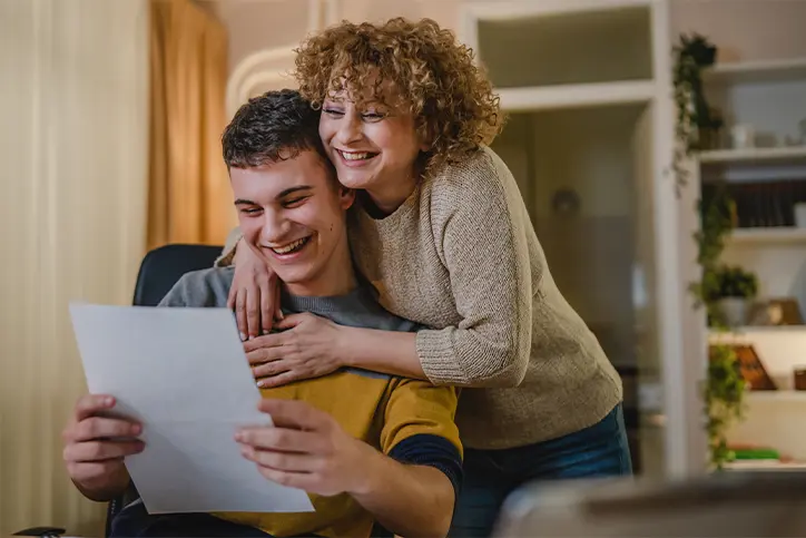Mom hugging her son who is holding a letter