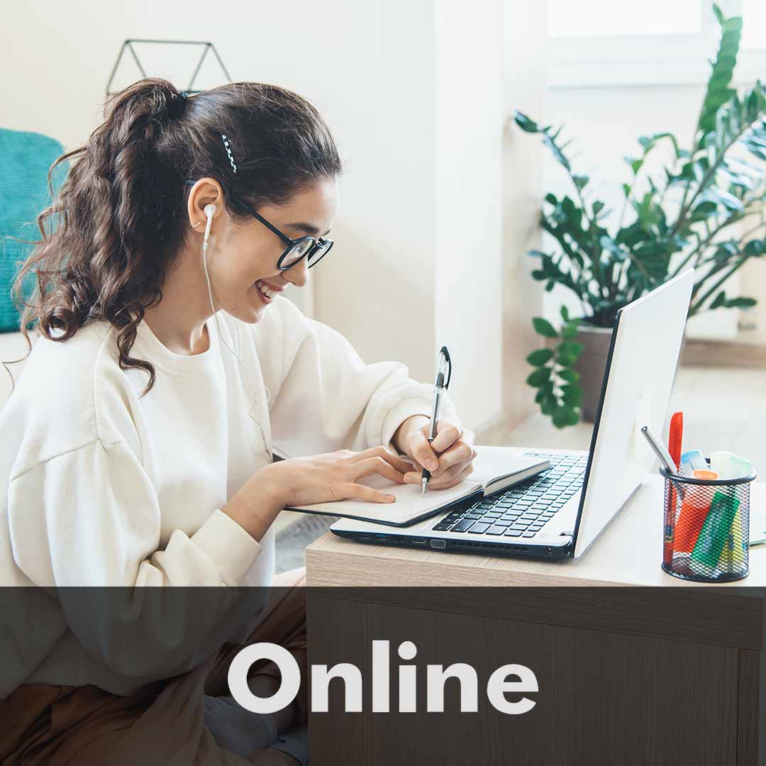 The word Online is written across the bottom of the image as a header. Photo of a girl smiling, sitting on the floor of her living room in front of a laptop.