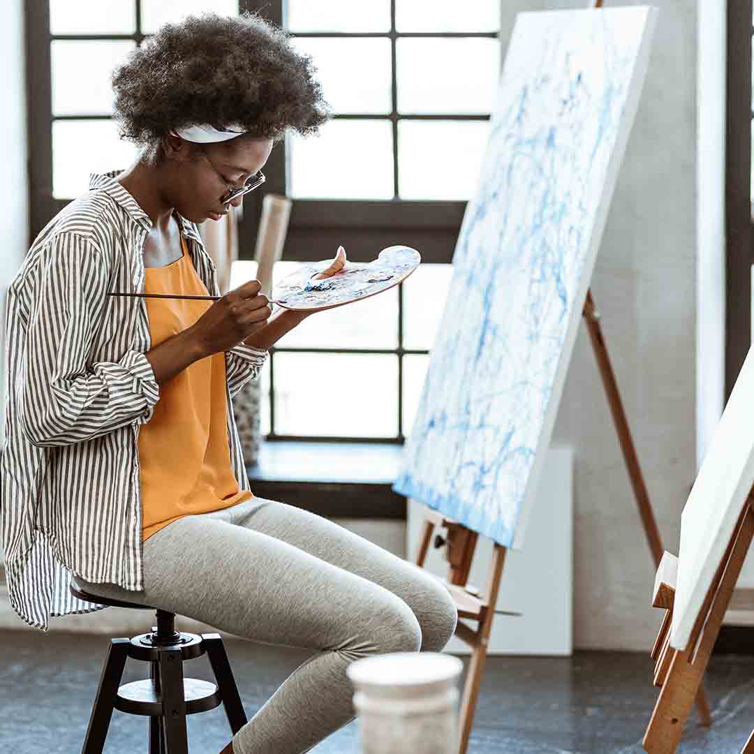 Woman sitting in front of a canvas painting