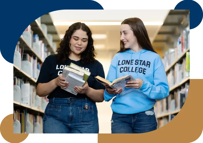 Two students holding books and smiling