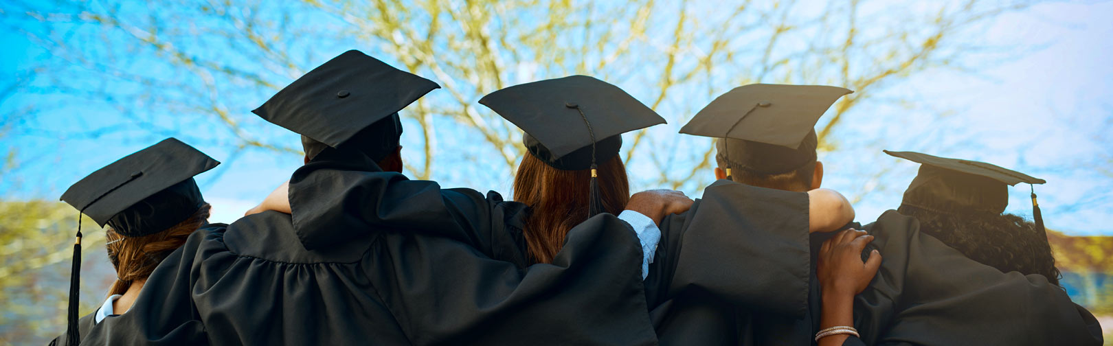 Students in cap and gown hugging each other as they look toward the future