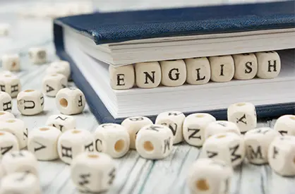 book laying on its side being held open by alphabet dice spelling english